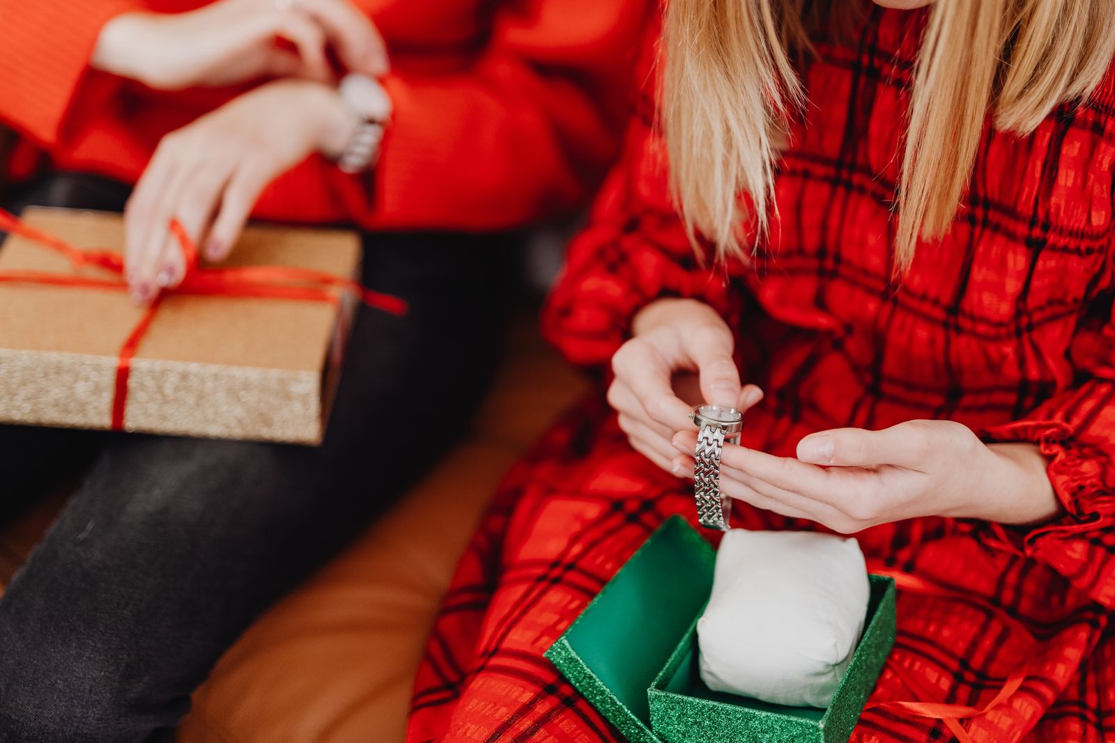 Two people exchanging wrapped gifts and jewellery at Christmas