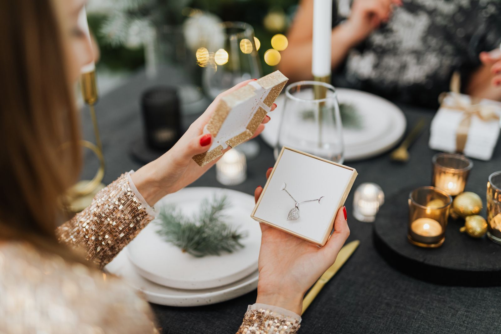 Woman opening a jewellery gift box at a Christmas table