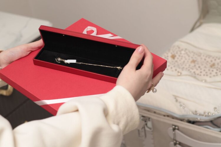 Red jewellery gift box holding a fine gold chain