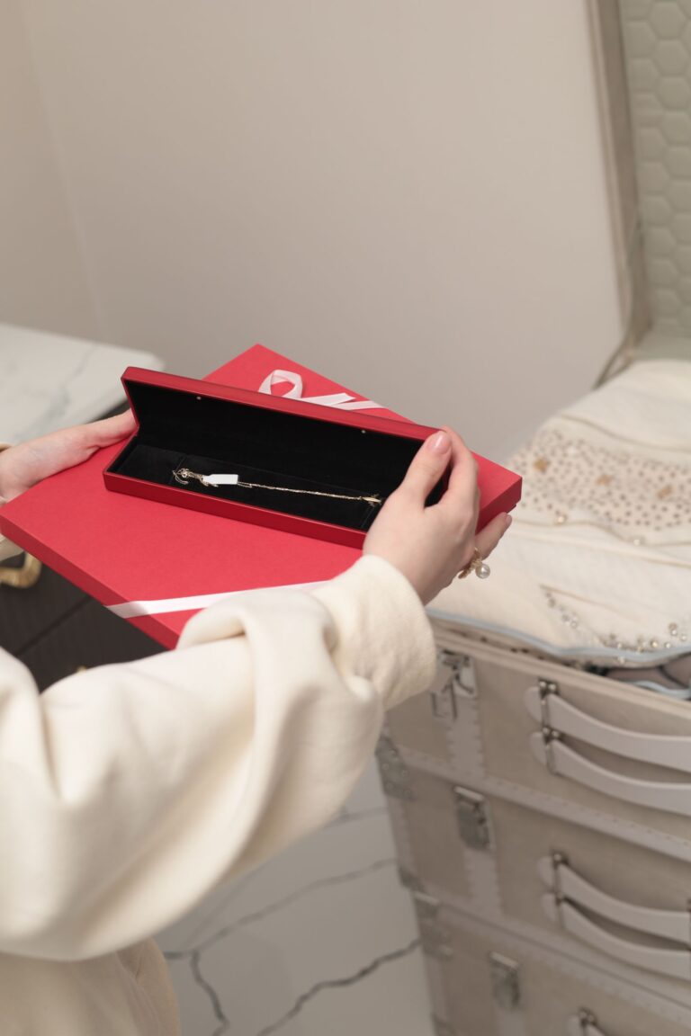 Red jewellery gift box holding a fine gold chain