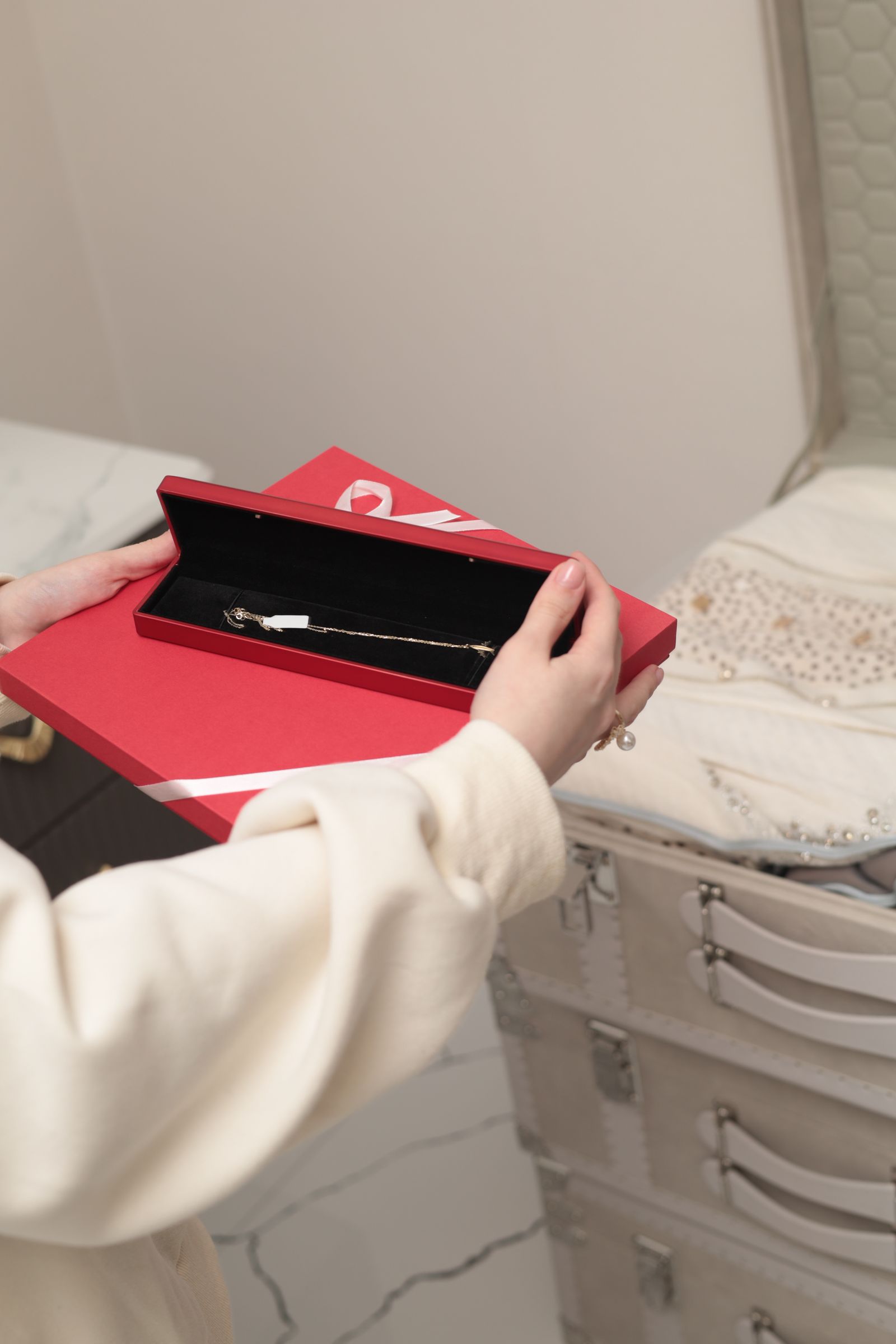Red jewellery gift box holding a fine gold chain