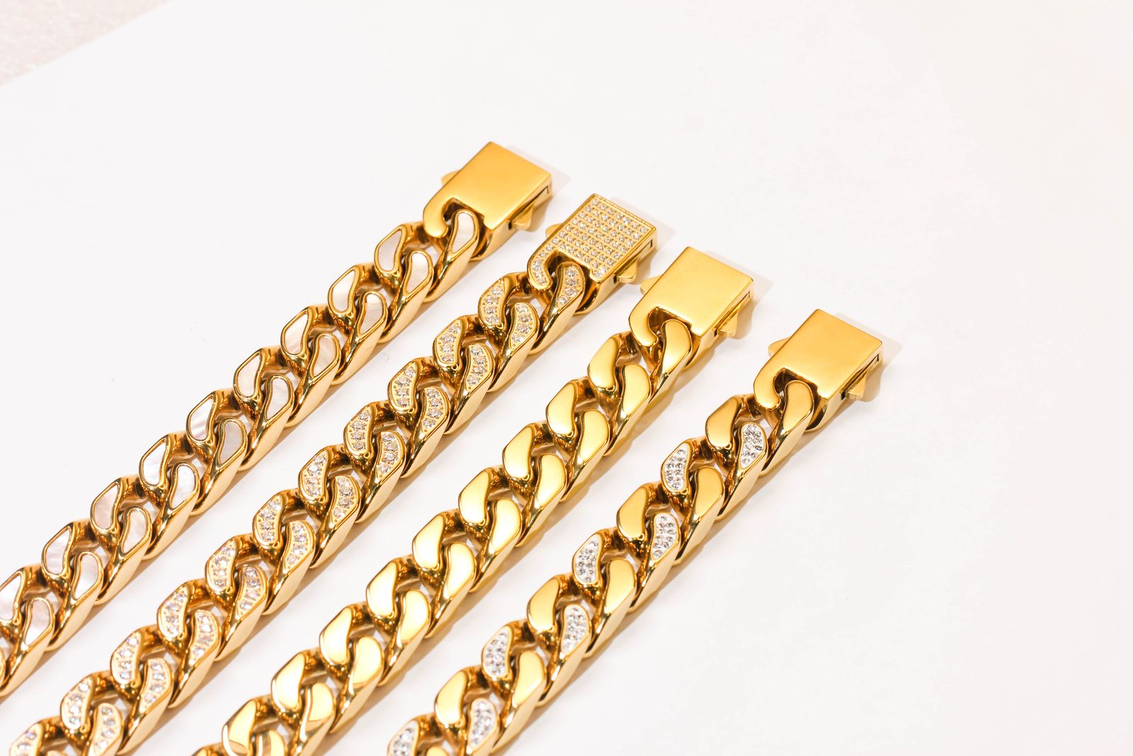 Chunky gold curb chain necklaces on a white surface