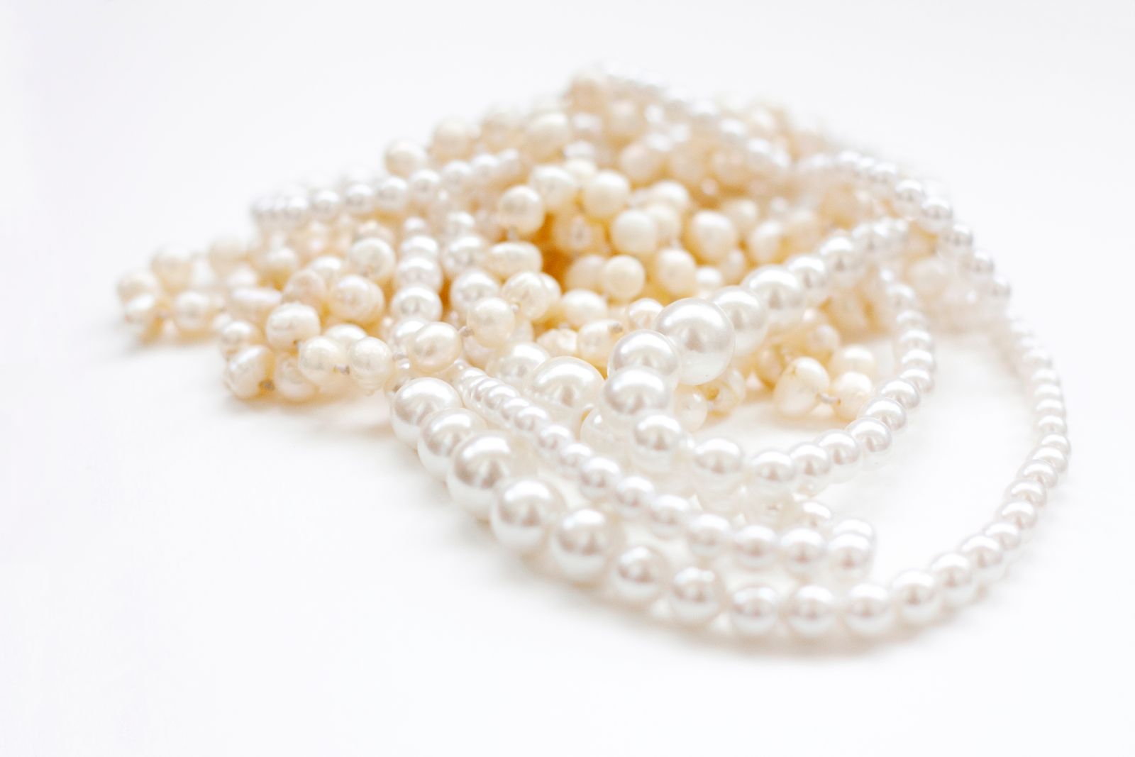 Strands of white pearls in mixed sizes on a white background