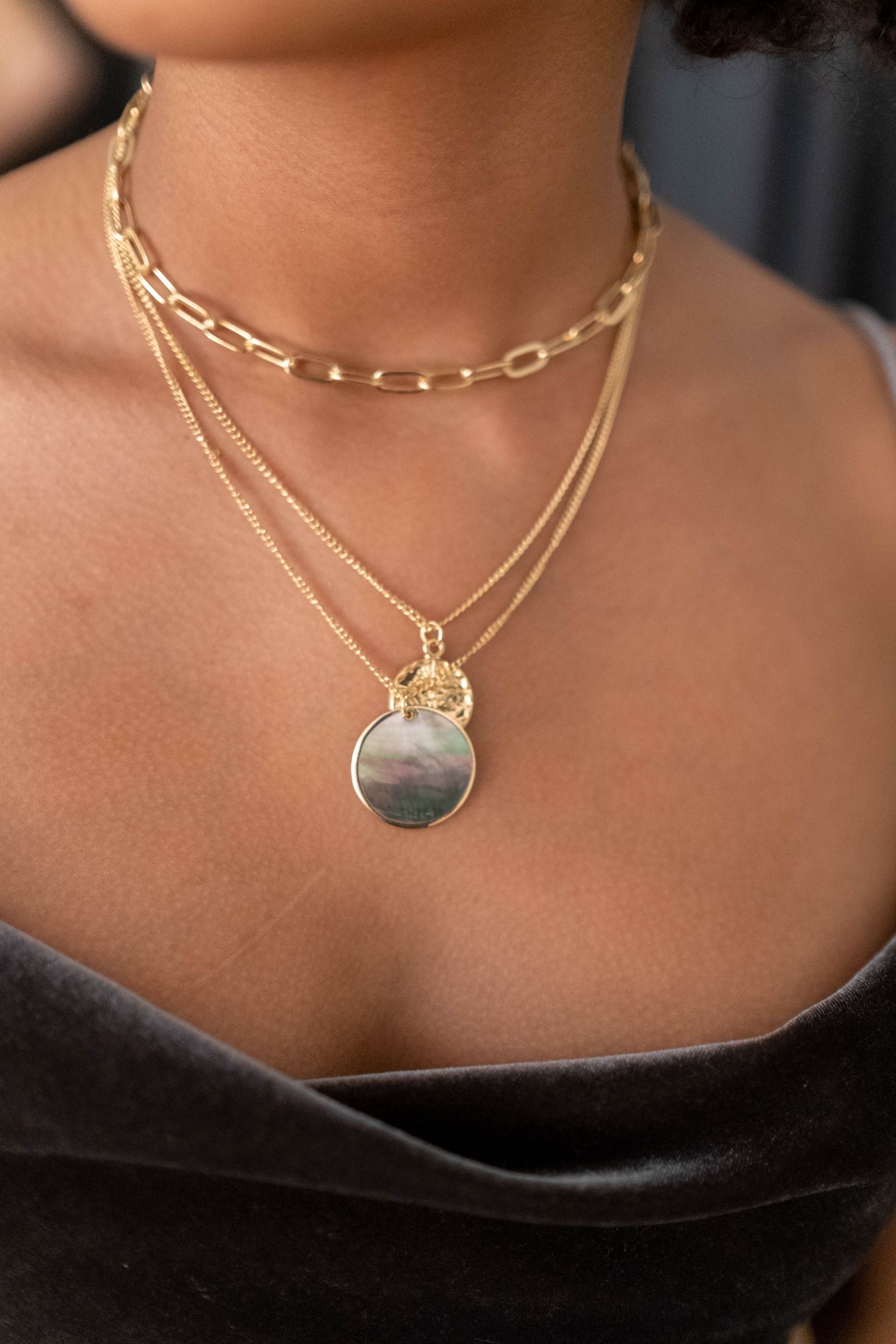 Layered gold chains with a mother of pearl medallion pendant